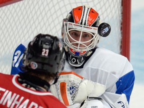 Finland's goalie Juuse Saros keeps his eyes on the puck under pressure from Canada's Sam Reinhart during first period semi-final IIHF World Junior Hockey Championship action in Malmo, Sweden on Saturday, January 4, 2014. THE CANADIAN PRESS/Frank Gunn