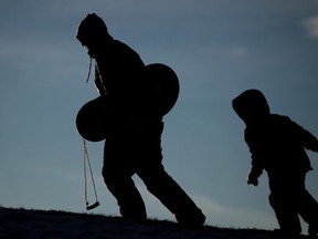 Jason Brimm, left, walks up the hill with his son, Gavin Brimm, 5, where they were tobogganing at Long Park, Friday, January 3, 2014.  Environment Canada is forecasting more snow for the region with up to 20 cm coming Sunday afternoon and evening.  (DAX MELMER/The Windsor Star)