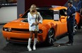 Model Sarrah Fegan, left, in front of Limited Edition 2014 Challenger, complete with Hemi engine and shaker hood during NAIAS at Cobo Center, Detroit, January 13, 2014. Brett Blenman, right, a delivery and setup specialist, checks out the Challenger's specs. (NICK BRANCACCIO/The Windsor Star)