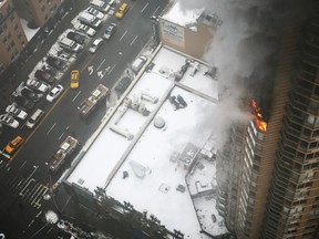 Flames and smoke emerge from the 20th floor of the Strand apartment building near Times Square, Sunday, Jan. 5, 2014 in New York. Authorities say two people have been critically injured in the three-alarm highrise fire. (AP Photo/Katherine Bourbeau)