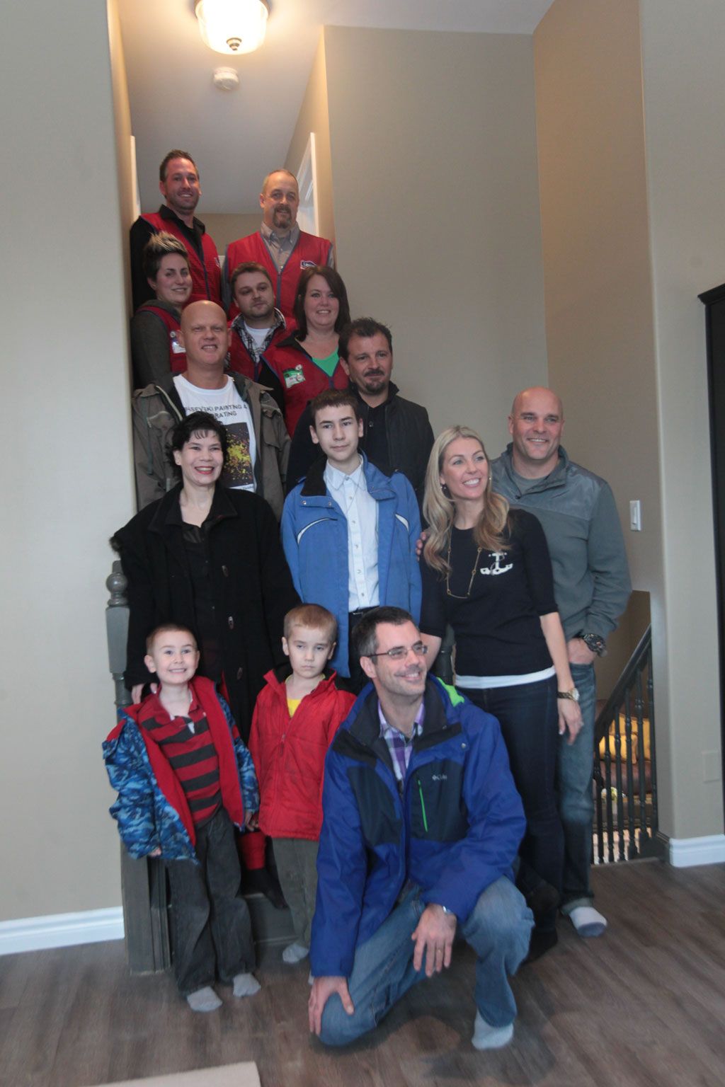 Michael and Cynthia Jamieson along with sons Noah,  Reid and Grayson,  Bryan and Sarah Baeumler of Baeumler Family Foundation for Kids,  Gino Piccioni from Timberland Homes, along with Lowes employees, gather for a photo after the family had their first glimpse of their restored home on Monday, Jan. 13, 2014.  (JASON KRYK/The Windsor Star)