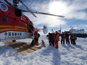 In this photo provided China's official Xinhnua News Agency, passengers from the trapped Russian vessel MV Akademik Shokalskiy, seen at right, prepare to board the Chinese helicopter Xueying 12 in the Antarctic Thursday, Jan. 2, 2014. A helicopter rescued all 52 passengers from the research ship that has been trapped in Antarctic ice, 1,500 nautical miles south of Hobart, Australia, since Christmas Eve after weather conditions finally cleared enough for the operation Thursday. (AP Photo/Xinhua, Zhang Jiansong)
