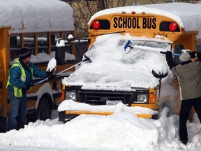 Duncan Bena, left, and Alvin Querin remove snow and ice from school buses at First Student Canada in West Windsor, Monday January 6, 2014.   About 100 buses never made it out of the parking lot, as school boards cancelled buses due to heavy snowfall in the area.  (NICK BRANCACCIO/The Windsor Star).