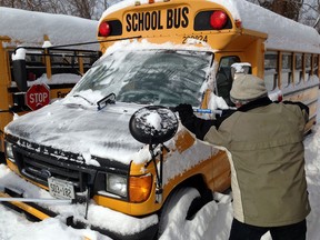 Alvin Querin  removes snow and ice from school buses at First Student Canada in West Windsor, Monday January 6, 2014.   About 100 buses never made it out of the parking lot, as school boards cancelled buses due to heavy snowfall in the area.  (NICK BRANCACCIO/The Windsor Star)