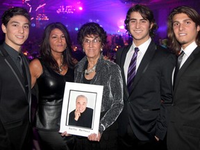 Carol-Lee Martinos, centre, holds a picture of her husband, Martin, at the 17th annual Transition to Betterness gala at the Ciociaro Club Saturday, Jan. 25, 2014. Carol-Lee’s daughter Ramza Saruna and three grandsons, Troy, 16, left, Zak, 18, and Mike, 21, were in attendance to celebrate the life of Martin. (JOEL BOYCE/The Windsor Star)