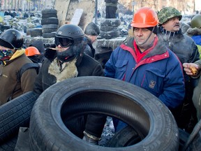 Protesters look at riot police from a barricade in central Kiev, Ukraine, Thursday, Jan. 30, 2014. Ukraine's embattled President Viktor Yanukovych is taking sick leave, his office announced Thursday, leaving it unclear how involved he may be in efforts to resolve the country's political crisis in which protesters are calling for his resignation. (AP Photo/Darko Bandic)