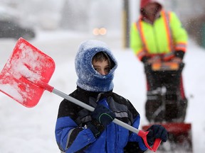 R.J. Marmus, 10, helped his father Chris Marmus on Prince Road as snow and wind hits the Windsor area Thursday January 2, 2014. (NICK BRANCACCIO/The Windsor Star)