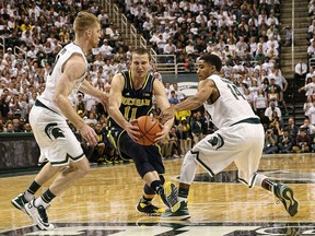 Mississauga's Nik Stauskas, centre, is guarded by MSU's Russell Byrd, left, and Gary Harris of the Michigan State Spartans Saturday at the Breslin Center n East Lansing. (Photo by Leon Halip/Getty Images)