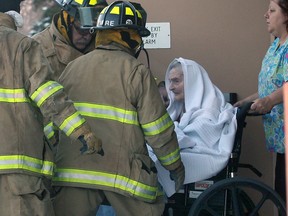 Firefighters help an elderly resident leave Brouillette Manor in a wheelchair on Jan. 8, 2014. (Dan Janisse / The Windsor Star)