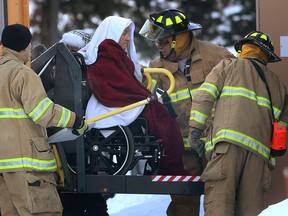 Firefighters help to move a senior resident of Brouillette Manor in Tecumseh, Ont. on Jan. 8, 2014. (Dan Janisse / The Windsor Star)