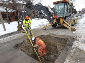 Enwin Utilities workers J.P. Pilon (L) and John Friest repair a broken water line Friday, Jan. 24, 2014, in the 400 block of Hall Ave. in Windsor, Ont. The extreme cold temperatures are to blame for the breakage they said.  (DAN JANISSE/The Windsor Star)