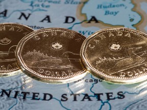 Loonies are displayed on a map of North America Thursday, January 9, 2014.  (Paul Chiasson/The Canadian Press)
