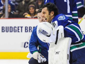 Canucks goalie Roberto Luongo, right, reacts after being hurt during play against the Boston Bruins during an NHL game at Rogers Arena on December 14, 2013 in Vancouver. (Derek Leung/Getty Images)