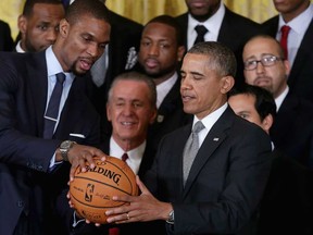 NBA champion Miami Heat player Chris Bosh, left, presents President Barack Obama with a signed basketball during an event at the White House January 14, 2014 in Washington, DC. (Chip Somodevilla/Getty Images)