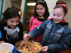 Allyssa Artale, 8, left, Eloha Volisiyar, 8, and Kaylee Foesenek, 9, cook stuffed peppers at Edible Fun at the YMCA in downtown Windsor. (DAX MELMER / The Windsor Star)