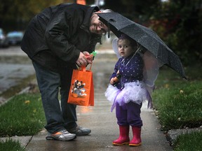 Emily Sanford Godden, two, and her dad Paul Sanford, of Windsor, go trick-or-treating on a rainy Halloween night in 2013. A new study says Canadian dads are more involved, claiming new territory in domestic life, and taking parental leave at an unprecedented rate. (DAN JANISSE/Windsor Star files)