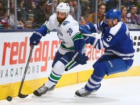 Toronto's Dion Phaneuf, right, checks Vancouver's Chris Higgins Saturday at the Air Canada Centre. (Photo by Abelimages/Getty Images)