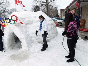 John Nicoletti, left, Lori Nicoletti, Kristina Nicoletti and Curtis Pluimers make some repairs to their Olympic-themed igloo in front of their home in Windsor, Ont. on Monday, Feb. 17, 2014. The igloo was the idea of their son Brian who recruited the entire family to help construct it over a five-day period. (TYLER BROWNBRIDGE/The Windsor Star)