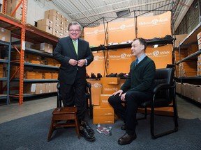 Finance Minister Jim Flaherty tries on a pair of shoes with Andrew Violi, president of Mello Walk Shoes, at a pre-budget press event in Toronto on Friday, February 7, 2014. (THE CANADIAN PRESS/Aaron Vincent Elkaim)