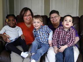 In a March 5, 2013, file photo, April DeBoer, second from left, sits with her adopted daughter Ryanne, left, 3, and Jayne Rowse, fourth from left, and her adopted sons Jacob, 3, middle, and Nolan, 4, right, at their home in Hazel Park, Mich. On Tuesday, Feb. 25, 2014, U.S. District Judge Bernard Friedman is scheduled to open a trial on the women’s challenge to Michigan’s ban on gay marriage and joint adoptions by same-sex couples. (AP Photo/Paul Sancya, File)