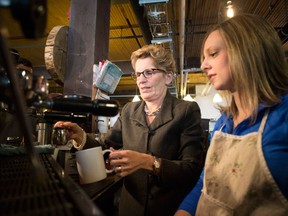 Ontario Premier Kathleen Wynne, left, is shown how to brew a cup of coffee at 'The Coffee Pub' by owner Erin Cluley, on Thursday,  January 30, 2014. The premier announced Ontario's minimum wage will be increased to $11 an hour effective June 1, up 75 cents. (THE CANADIAN PRESS/Chris Young)