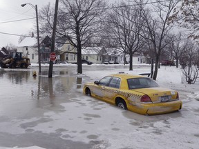 A taxi cab is surrounded by water on a flooded street after a water main break in Detroit on Tuesday, Feb. 11, 2014. The broken water main flooded a several-block area in southwest Detroit, trapping several cars. (AP Photo/Carlos Osorio)