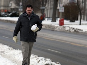 Roy Fells walks along a snow covered sidewalk in Windsor on Monday, February 10, 2014. The city is cracking down on and ticketing property owners who have failed to remove the snow from their sidewalks.                                  (TYLER BROWNBRIDGE/The Windsor Star)