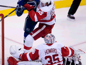 Vancouver's Ryan Kesler, left, checks Detroit's Danny DeKeyser in front of Wings goalie Jimmy Howard. (THE CANADIAN PRESS/Jonathan Hayward)