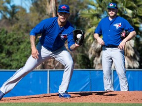 Toronto Blue Jays pitcher Mark Buehrle, right, looks on as Sergio Santos fields a ball at spring training in Dunedin, Fla., on Tuesday, February 18, 2014. (THE CANADIAN PRESS/Frank Gunn)