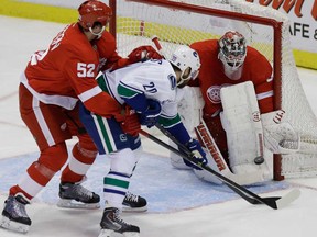 Vancouver's Chris Higgins, centre, battles Detroit's Jonathan Ericsson, left, in front of Wings goalie Jonas Gustavsson in Detroit, Monday, Feb. 3, 2014. (AP Photo/Carlos Osorio)