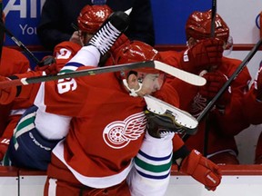 Detroit's Tomas Jurco, centre, takes a skate in the face after checking Vancouver's Alexander Edler during NHL action in Detroit, Monday, Feb. 3, 2014. (AP Photo/Carlos Osorio)