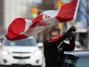 A man waves the Canadian flag while parading up and down Ouellette Ave. after Canada won the gold medal in men's hockey at the 2014 Winter Olympics in Sochi, Russia, Sunday, Feb. 23 , 2014. (DAX MELMER/The Windsor Star)