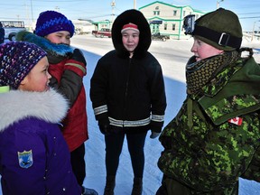 Corporal Jamie Scott from the Windsor Regiment talks to local children during a presence patrol in Rankin Inlet, Nunavut part of Exercise TRILLIUM RESPONSE on Thursday February 20, 2014. (Courtesy of Canadian Army Public Affairs)