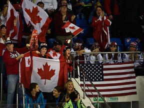 Canadian fans cheers and Team USA fans sit quietly after Canada scored the game winning goal during third period action at the Sochi Winter Olympics Wednesday February 12, 2014 in Sochi, Russia. Canada defeated Team USA 3-2. THE CANADIAN PRESS/Adrian Wyld