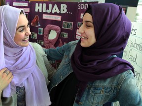 Sarah Mitchell, left, third-year University of Windsor student tries on a hijab with the help of Heba Zubaidi during the first day of Islam Awareness Week at the CAW Centre Monday March 10, 2014.  (NICK BRANCACCIO/The Windsor Star)