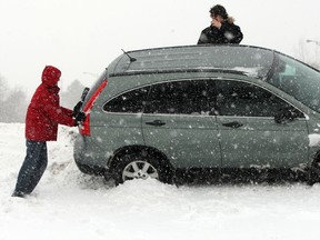 Driver and passenger of a four-door SUV assess their next move after sliding off the west bound E. C. Row Expressway during Wednesday's snow storm. The passenger mention they had a working cell phone, March 12, 2014. (NICK BRANCACCIO/The Windsor Star)