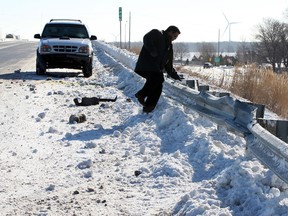 Motorist Alvin Jugoon of Windsor, jumps over the guardrail to retreave parts from his Ford Explorer following a collision on Hwy. 401 near Exit 40, Thursday March 13, 2014. Jugoon reported thick patches of ice still remained on the roadway following yestderday's snowstorm. He also warned that other motorist to slow down. (NICK BRANCACCIO/The Windsor Star)