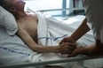 In this file photo, a nurse holds the hand of an elderly patient at a palliative care unit in this file photo. (Fred Dufour/AFP/Getty Images)