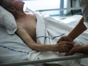 In this file photo, a nurse holds the hand of an elderly patient at a palliative care unit in this file photo. (Fred Dufour/AFP/Getty Images)