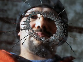 Belleview Avenue homeowner Scott Gillen looks through the bullet hole in his front picture window on March 24, 2014. (Tyler Brownbridge / The Windsor Star)