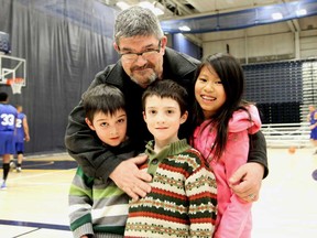 Francis Ryall hugs three of his four kids, Quinn, from left, Killian and Molly, at the charity basketball game between the Windsor Lancers and Windsor police at the St. Denis Centre Saturday, March 22, 2014. (JOEL BOYCE/The Windsor Star)