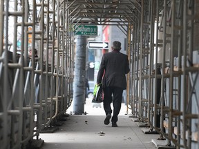 A pedestrian walks through scaffolding surrounding the Paul Martin Building in downtown Windsor, Ont. on Thursday, March 20, 2014. (DAN JANISSE/The Windsor Star)