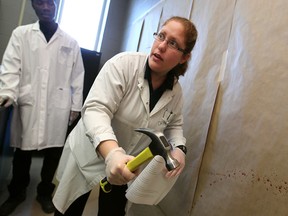 Forensics student Danielle Yardeni demonstrates bloodstain pattern analysis. Fellow student Jeremiah Boateng looks on. Photographed March 21, 2014 at the University of Windsor. (Dax Melmer / The Windsor Star)