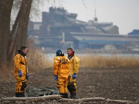 LaSalle firefighters stand over the covered body of an American male that was found floating in the Detroit River near Old Front Rd. in LaSalle, Saturday, March 29, 2014.  (DAX MELMER/The Windsor Star)