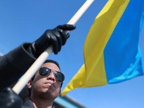 In this file photo, Miguel Vigil holds up a Ukrainian flag as he joins over a hundred people at a rally at Lanspeary Park to show support for the people of Ukraine, Sunday, March 9, 2014.  (DAX MELMER/The Windsor Star)