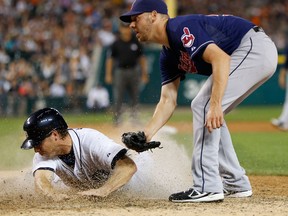 Detroit's Andy Dirks, left, scores on wild pitch by Cleveland's Rick Hill at Comerica Park. (Photo by Gregory Shamus/Getty Images)