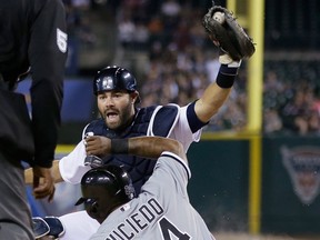 Tigers catcher Alex Avila, top, holds up the ball to umpire C.B. Bucknor after tagging Chicago runner Dayan Viciedo during the seventh inning Monday in Detroit. Viciedo was called safe after the umpire review. (AP Photo/Carlos Osorio) ORG XMIT: MICO110