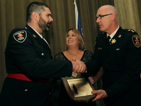 Police Const. Lance Montigny, left, is congratulated by Windsor police Chief Al Frederick and Shelly Atkinson, centre, after receiving the Senior Constable John Atkinson Memorial Award at the 16th Annual 911 Community Service Awards at the Caboto Club, Thursday, April 3, 2014.  (DAX MELMER/The Windsor Star)