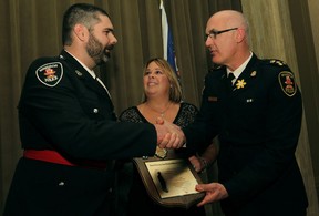 Police Const. Lance Montigny, left, is congratulated by Windsor police Chief Al Frederick and Shelly Atkinson, centre, after receiving the Senior Constable John Atkinson Memorial Award at the 16th Annual 911 Community Service Awards at the Caboto Club, Thursday, April 3, 2014.  (DAX MELMER/The Windsor Star)