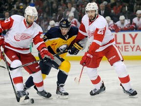 Detroit's Kyle Quincy, left, and Drew Miller, right, check Buffalo's  Torrey Mitchell Tuesday in Buffalo. (AP Photo/Gary Wiepert)